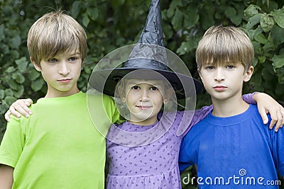 Serious twins and girl in carnival hat Stock Photo