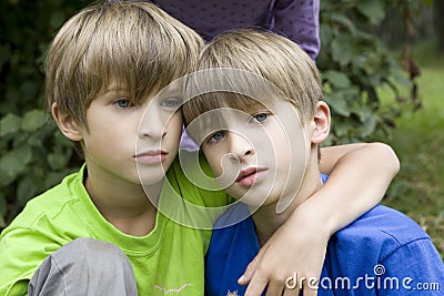 Serious twins hugging in park Stock Photo