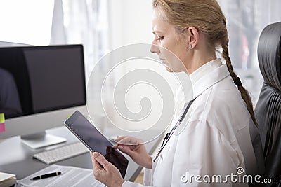 Serious Woman Clinician Using Tablet at her Office Stock Photo