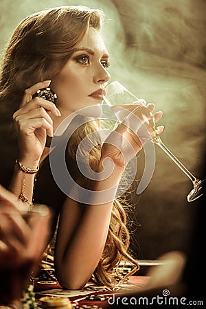 Serious woman with drink and poker chip playing poker Stock Photo