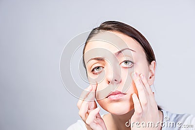 Serious Woman Pulling Down her Lower Eyelids Stock Photo