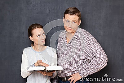 Serious woman is trying to pay attention of man to info in book Stock Photo