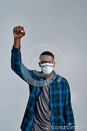 Serious young african american guy wearing protective mask with inscription BLM looking at camera, posing with raised Editorial Stock Photo