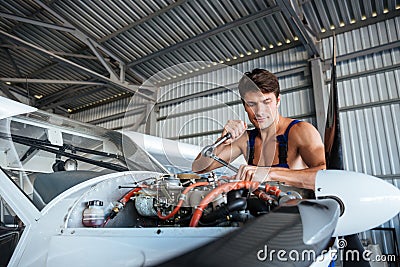 Serious young aircraft mechanic fixing small airplane Stock Photo