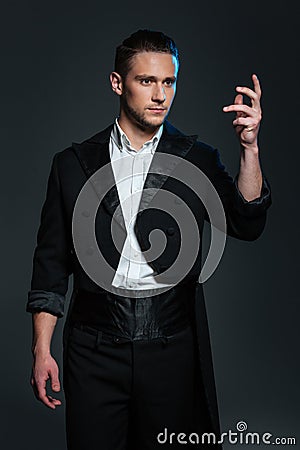 Serious young man magician in black tail coat showing tricks Stock Photo
