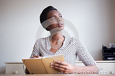 Serious young woman thinking and writing in journal Stock Photo