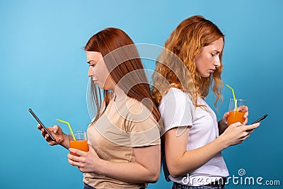 Serious young women reading daily, important news on smartphones drinking cocktails. Students, friends using modern Stock Photo