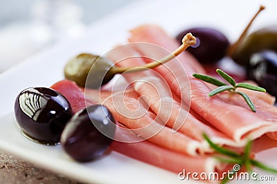 Serrano ham with olives and caper berries Stock Photo