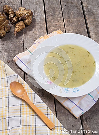 Served soup of Jerusalem artichoke in plate with wooden spoon Stock Photo