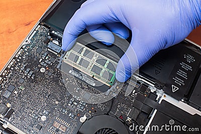 Service engineer install new RAM memory chips to the laptop. Repairing and upgrading laptop concept. Close up view Stock Photo