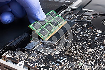 Service engineer install new RAM memory chips to the laptop. Repairing and upgrading laptop concept. Close up view Stock Photo