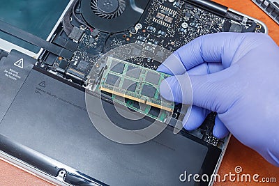 Service engineer install new RAM memory chips to the laptop. Repairing and upgrading laptop concept. Close up view Stock Photo