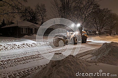 Service snow plowing truck cleaning residential street during heavy snowstorm, Toronto, Ontario, Canada. Editorial Stock Photo