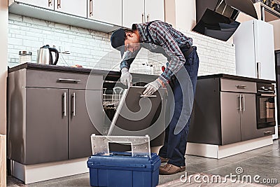 Service in time. Male technician sitting near dishwasher Stock Photo