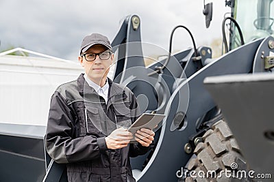 Serviceman with digital tablet on a background of the tractor Stock Photo