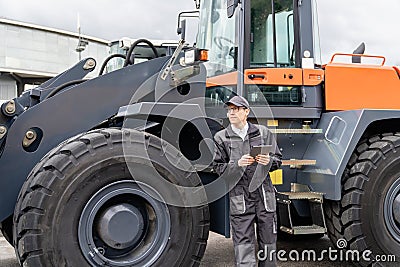 Serviceman with digital tablet on a background of the tractor Stock Photo
