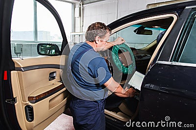 Serviceman making car diagnostics with laptop Stock Photo