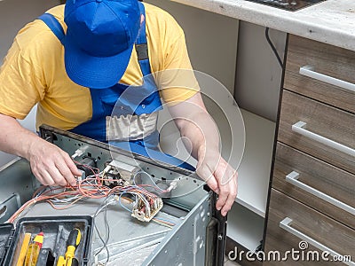 Serviceman replacing faulty part in the electric oven Stock Photo