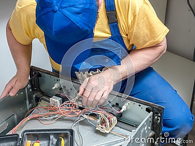 Serviceman replacing thermostat in the electric oven Stock Photo