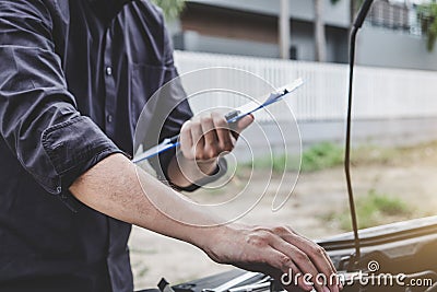 Services car engine machine concept, Automobile mechanic repairman checking a car engine with inspecting writing to the clipboard Stock Photo