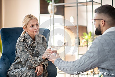 Servicewoman taking glass of water from psychologist Stock Photo