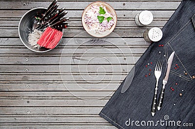 Serving background on dark grey metal background with space for text. Top view Knife and fork wrapped on a denim napkin Stock Photo
