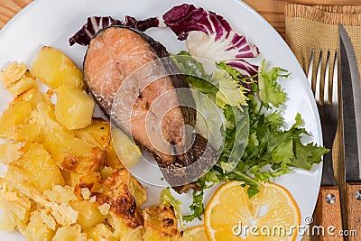 Serving of baked rainbow trout with potato, fragment close-up Stock Photo