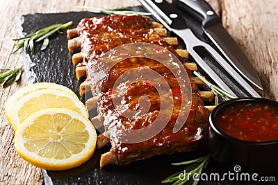 Serving BBQ pork ribs with chili sauce and lemon close up on a slate board. horizontal Stock Photo