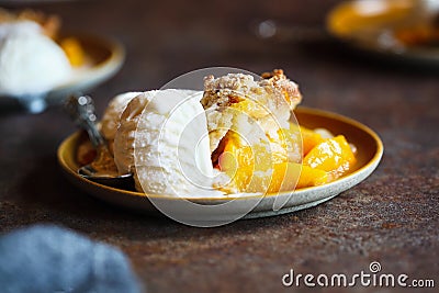 Serving of Drop Biscuit Peach Cobbler and Melting Ice Cream Stock Photo