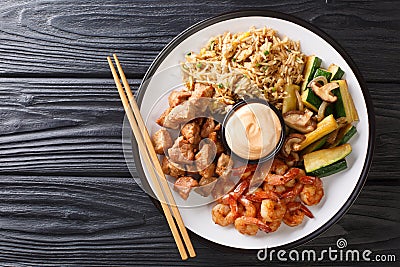 Serving hibachi of rice, shrimp, steak and vegetables served with sauce closeup in a plate. Horizontal top view Stock Photo