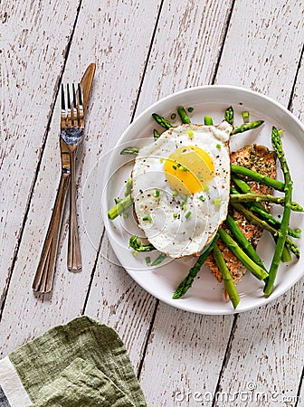 A serving of roasted salmon with sauteed asparagus and a fried egg on top. Stock Photo