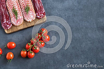 Serving of the slices of smoked sausages lie on a cutting board in several rows on a wooden stand. Stock Photo