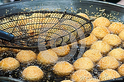 Sesame balls frying in hot oil Stock Photo