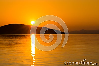 Sescape sunrise above calm water with island Stock Photo