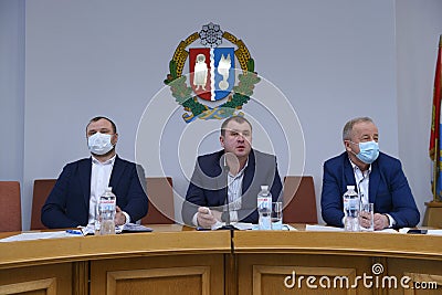 Session of regional council. Head center and his deputies with masks over faces sitting at the presidium and keeping speach Editorial Stock Photo