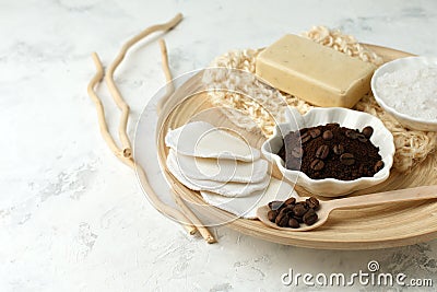 Set for anti-cellulite massage procedures. Coffee scrub, coffee grains, sea salt, soap, sponge on wooden plate and gray background Stock Photo