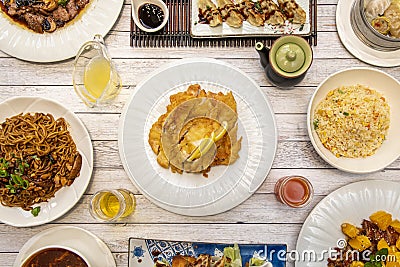 Set of Asian Chinese food recipes on white plates, lemon battered chicken, fried gyozas with soy sauce, duck with orange and fried Stock Photo
