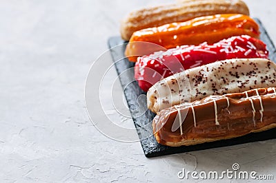 Set of assorted eclairs served on a slate board on a white stone Stock Photo