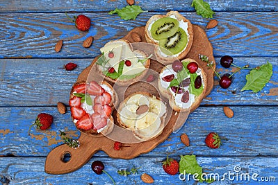 Set of assorted healthy wholewheat bread sandwiches with fruit, cheese and leafy green herbs on picnic wooden table Stock Photo