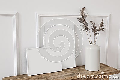 Set of blank white picture frame mockups. Vase with dry reed, grass on old wooden bench. Wall moulding background, trim Stock Photo