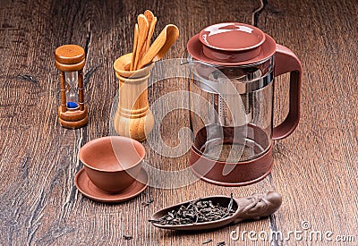 A set for brewing tea with a kettle, hourglass, wooden tools. Stock Photo