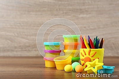 Set of bright play dough with tools and colorful pencils on wooden table. Space for text Stock Photo