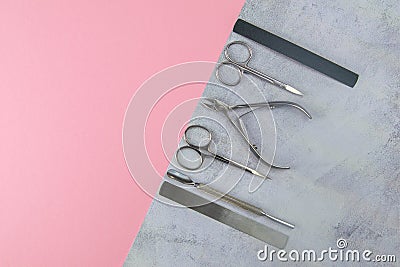 A set of cosmetic tools for manicure and pedicure. Manicure scissors, cuticles, saws, miller and towel stand on a concrete pink Stock Photo