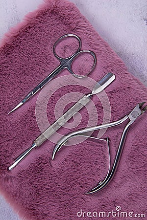 A set of cosmetic tools for manicure and pedicure stand on a pink fluffy notebook for recording clients. tweezers, scissors and Stock Photo