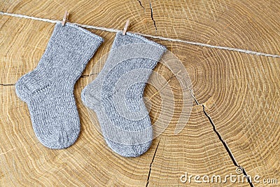 Set of cute knitted cashmere newborn baby socks hanged on pins against wooden background Stock Photo