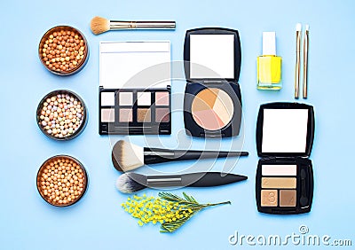 Set of decorative cosmetics for make-up Powder Rouge Eyeshadow Corrector Brushes and flowers of mimosa on blue background. Makeup Stock Photo