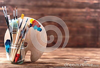 Set of different brushes and acrylic paints to paint scattered on a dark wooden table.Artist workplace background.Art tools.Creati Stock Photo