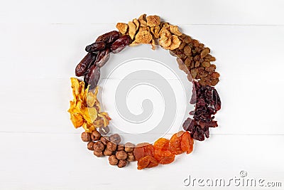 A set of dried berries, fruits and nuts in the form of a wreath hazelnut,pumpkin, cherry, apricot, Apple, dates, on a white Stock Photo