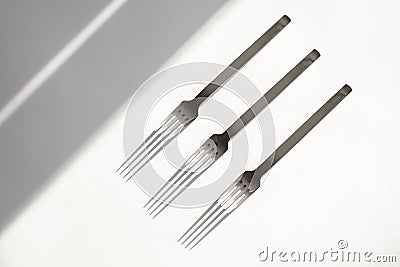 Set of forks on a white background with hard shadows from the sun`s rays. top view close-up. cutlery. Subject photography. Stock Photo