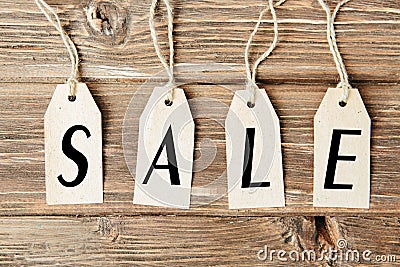 set of four tags with word SALE hanging on rope on wooden background Four paper blank tags with rope on wooden Stock Photo